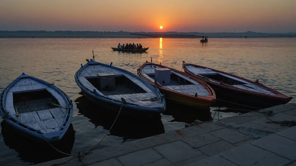 Wooden boats at a Varanasi ghat as the sun rises over the Ganga